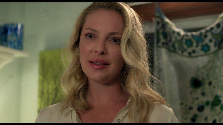 Katherine Heigl looking at something with her blonde hair down and wearing a white shirt in a scene from the 2021 movie "Fear of Rain"