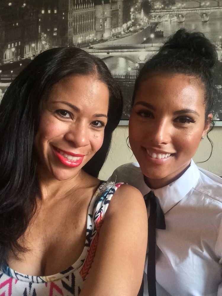 Felisha Cooper smiling and wearing white long sleeves and a woman beside her smiling and wearing colorful top