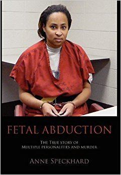 On a FETAL ABDUCTION is Lara being serious, has black hair, sitting down in a red chair in a room, both hands are handcuffed, below her is the description of “The True Story Of Multiple Personalities And Murder” by Anne Speckhard, she is wearing a white shirt and an orange inmate uniform with a black belt.