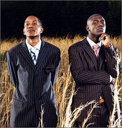 Shawn Jay wearing a blue striped coat, long sleeves, and necktie while Smoke wearing a black striped coat, white long sleeves, and necktie