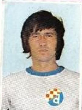Fikret Mujkić with a serious face and medium length hair while wearing a white and blue t-shirt