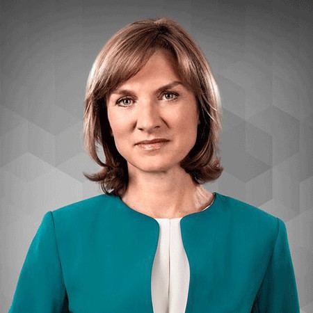 Fiona Bruce with short blonde hair, wearing a green coat and a white shirt.