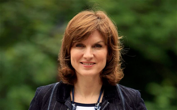 Fiona Bruce with blonde hair, wearing a black coat and a white and black inner shirt.