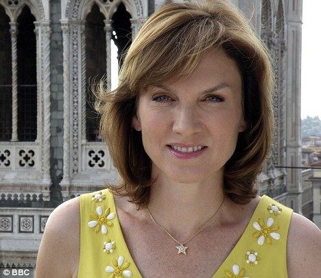Fiona Bruce with blonde hair, wearing a necklace and a yellow sleeveless top with floral design.
