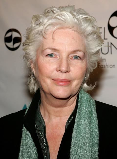 Fionnula Flanagan smiling closed mouth and wearing a black dress and a green scarf on her neck.