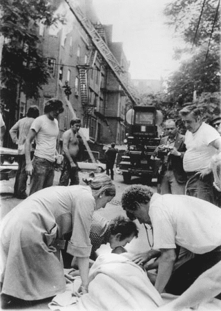 Diana Bryant's body lying on the ground and covered with a white cloth while people checking on her