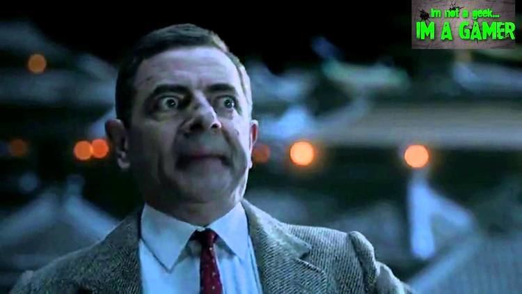 Rowan Atkinson as Mr. Bean with a shocked face, wearing a gray coat over white long sleeves and a red tie in a movie scene from Fist of Bean, a 1995 Chinese short Snickers commercial movie.