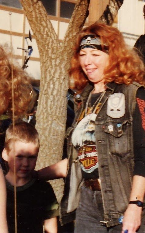 Florence Tullis with curly hair while wearing black headband, vest and black printed shirt