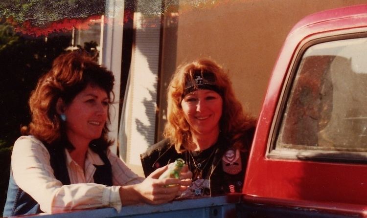 Florence Tullis smiling with her friend while wearing black headband and black printed shirt