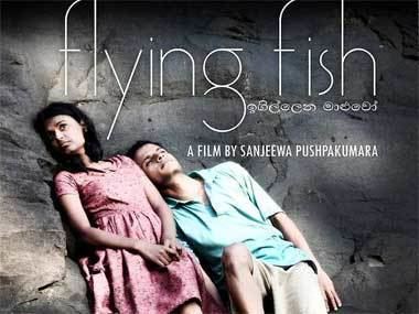 The movie poster of the 2011 anthology film "Flying Fish". Gayesha Perera and Nilanka Dahanayake are looking afar while leaning on a big rock with serious faces and dried leaves on their feet. Gayesha is wearing a pink dress while Nilanka is wearing a blue polo shirt and brown shorts