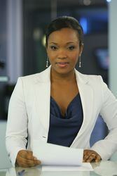 Folly Bah Thibault with a tight-lipped smile while wearing a white coat, blue inner blouse, and earrings