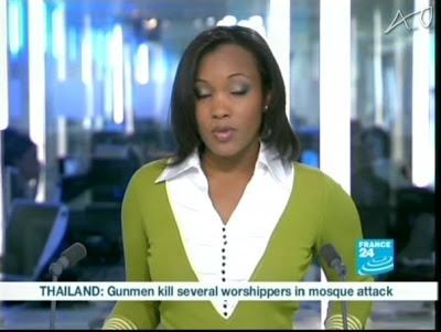Folly Bah Thibault reporting the news while wearing a green long sleeve and white blouse