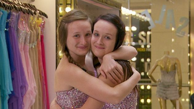 A scene of two smiling women hugging each other while wearing the same dress in reality tv series Formal Wars (2013)