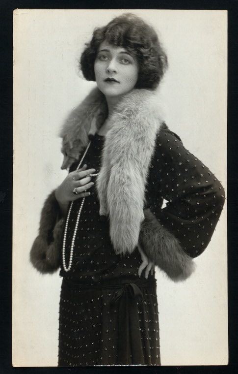 Frances Bavier with short wavy hair while wearing a long sleeve dress, fur scarf, and long pearl necklace