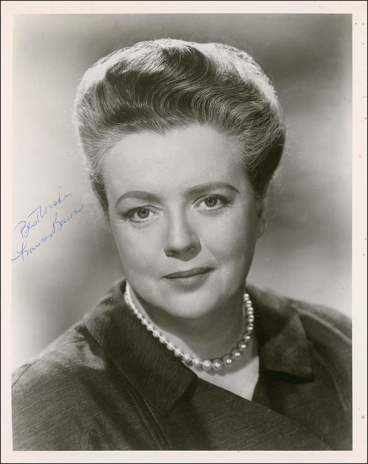 Frances Bavier with a tight-lipped smile and tied-up hair while wearing a pearl necklace and blouse