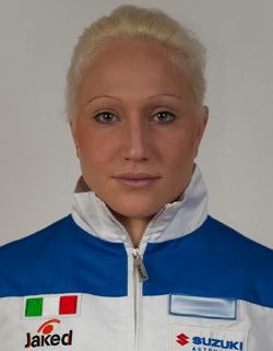 Francesca Lollobrigida with a tight-lipped smile, blonde hair, and wearing a multi-colored jacket.