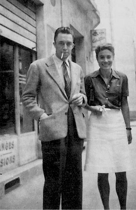 Albert Camus smoking with his right hand on his pocket, smiling beside  him is his wife Francine Faure