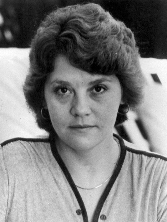 Black and white photo of Francine Hughes with short hair, wearing earrings and a necklace.