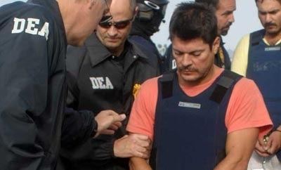 Francisco Javier Arellano Felix with a sad face, with the Coast Guardsmen, and wearing a blue vest and orange shirt.