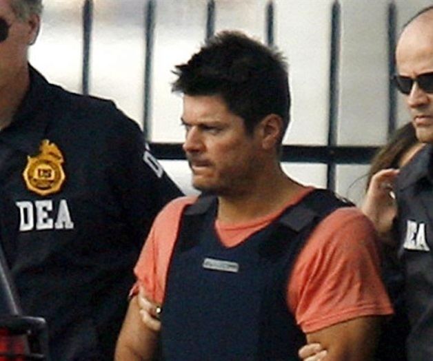 Francisco Javier Arellano Felix with a serious face with the Coast Guardsmen, wearing a blue vest and orange shirt.