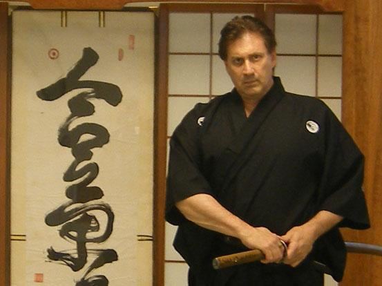 Frank Dux wearing black dobok while holding his weapon