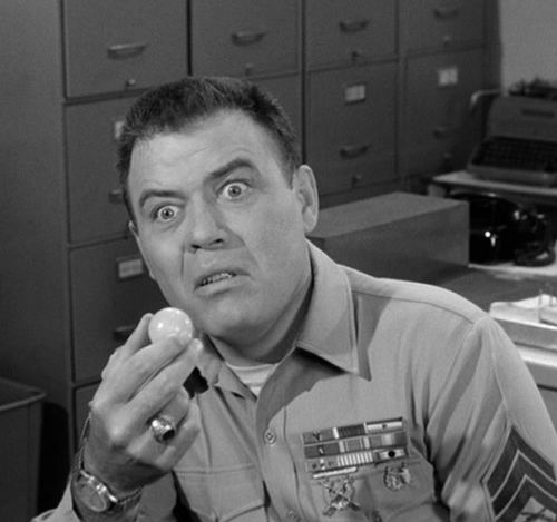 Frank Sutton as Sgt. Vince Carter with an angry face, holding food while wearing a ring and a watch.