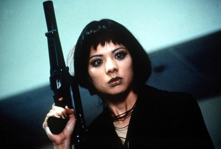 Françoise Yip in her black outfit while holding a gun