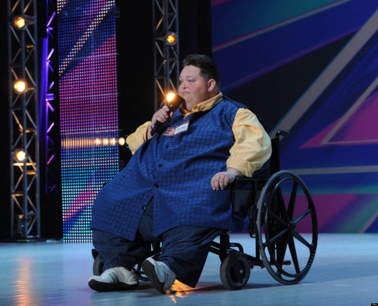 Freddie Combs in his wheelchair wearing yellow long sleeves and blue vest at The X Factor USA