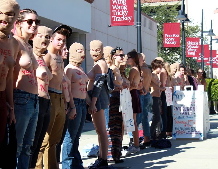 Topless men and women are in the street and some of them are wearing masks