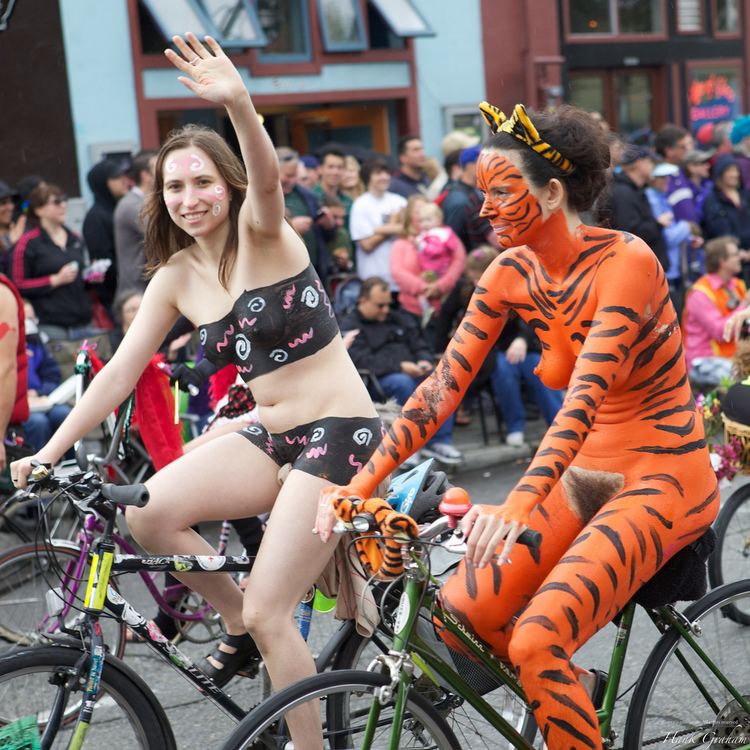 Fremont Solstice Parade featuring two ladies riding a bike with colorful body paintings.