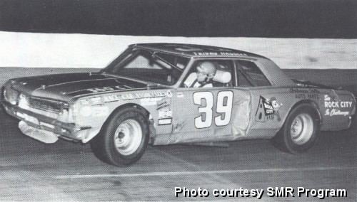 Friday Hassler driving a racing car with a No. 39 on it and wearing a white helmet.