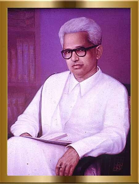 G. Sankara Kurup with a serious face and wearing eyeglasses and white long sleeves with a book on his lap.