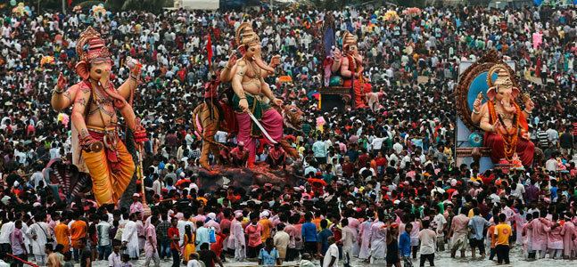 Four different statues of the Hindu God Ganesh being flocked by devotees celebrating the festival of Ganesh Chaturthi.