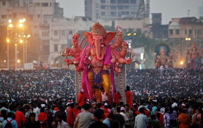 A statue of the Hindu God  Ganesh being flocked by devotees celebrating the festival of Ganesh Chaturthi.