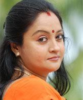 Geetha Vijayan wearing a necklace and an orange top.