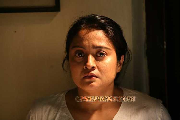 Geetha Vijayan with a sad face and wearing a white shirt.