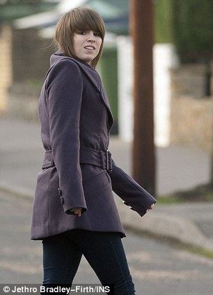 Gemma Barker walking down a street wearing a coat and sporting a boyish hair with bangs.