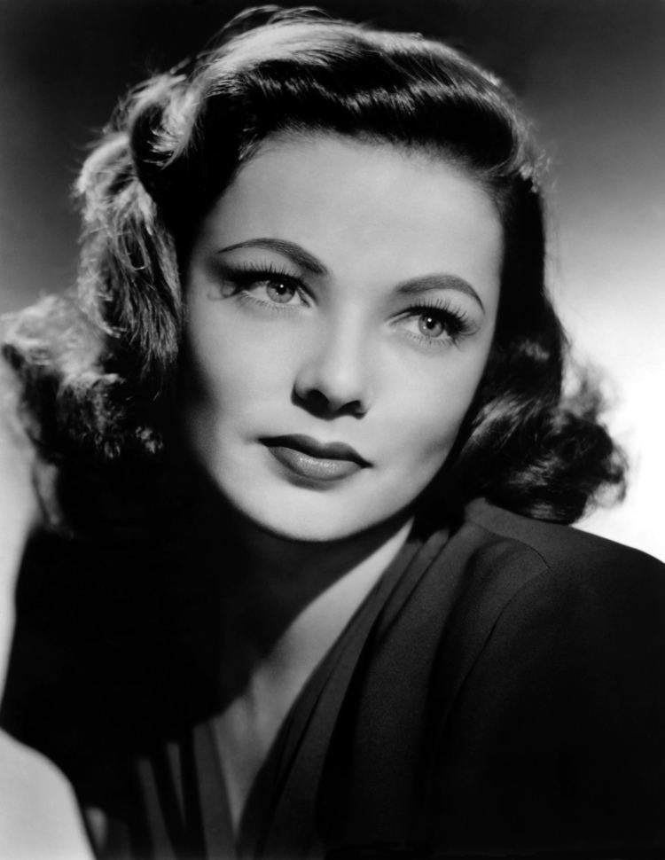 Gene Tierney with a tight-lipped smile, short wavy hair, and wearing a black top.
