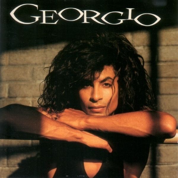 A poster featuring Georgio leaning against his arms with his long curly hair while wearing a black sleeveless