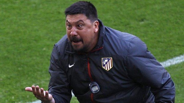 Germán Burgos with an angry face while moving his hand to the front, with beard and mustache, wearing a dark blue jacket with the logos of Nike and Atlético de Madrid, and a timer.