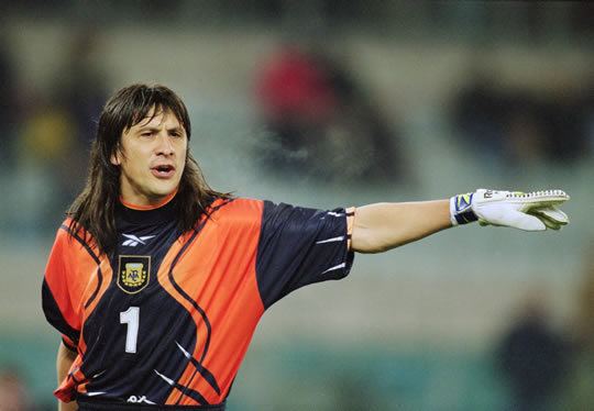 Germán Burgos talking while moving his arm to the side, with long hair, wearing a black and orange jersey with no. 1 printed on it, and white gloves.