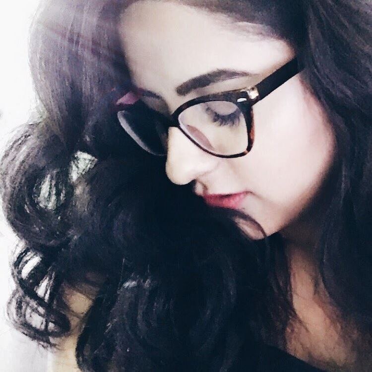 A girl with a closed eyes side view face pose has a black curly hair, wearing an eyeglasses