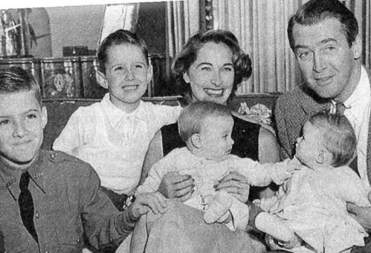 Gloria Hatrick McLean smiling while sitting on the couch with James Stewart and their four children