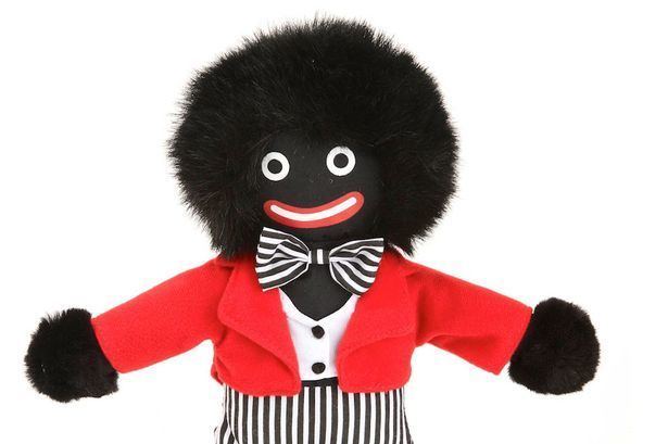 A standard male Golliwog rag doll, otherwise known as a Golly with its trademark red suit and striped pants.