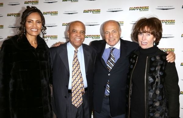 Berry Gordy Sr. posing together with companions and wearing a black suit along with a sky blue formal attire and multicolored tie.