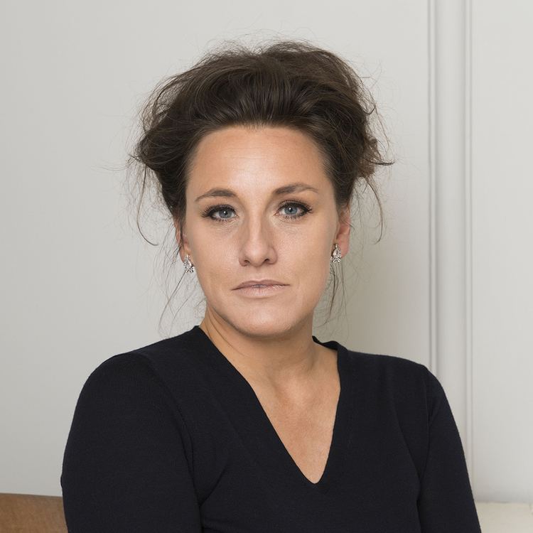 Grace Dent with messy hair while wearing a black blouse and earrings