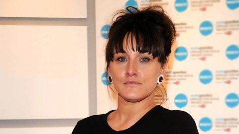 Grace Dent with a serious face while wearing a black blouse and earrings