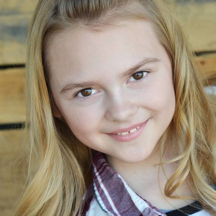 Gracie Prewitt smiling while wearing a white and maroon checkered blouse and black and white inner blouse