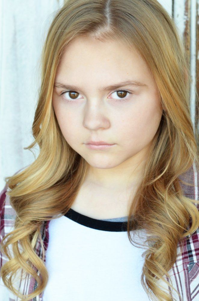 Gracie Prewitt with a serious face while wearing a white and maroon checkered blouse and black and white inner blouse