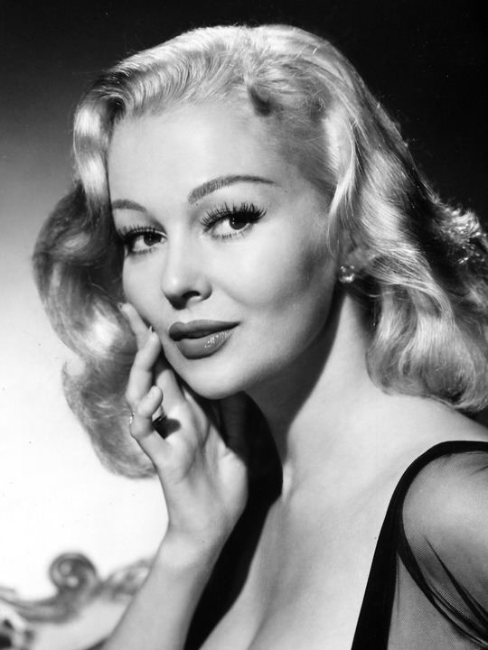 Greta Thyssen's curly hair and glamorous make up while hand on her face